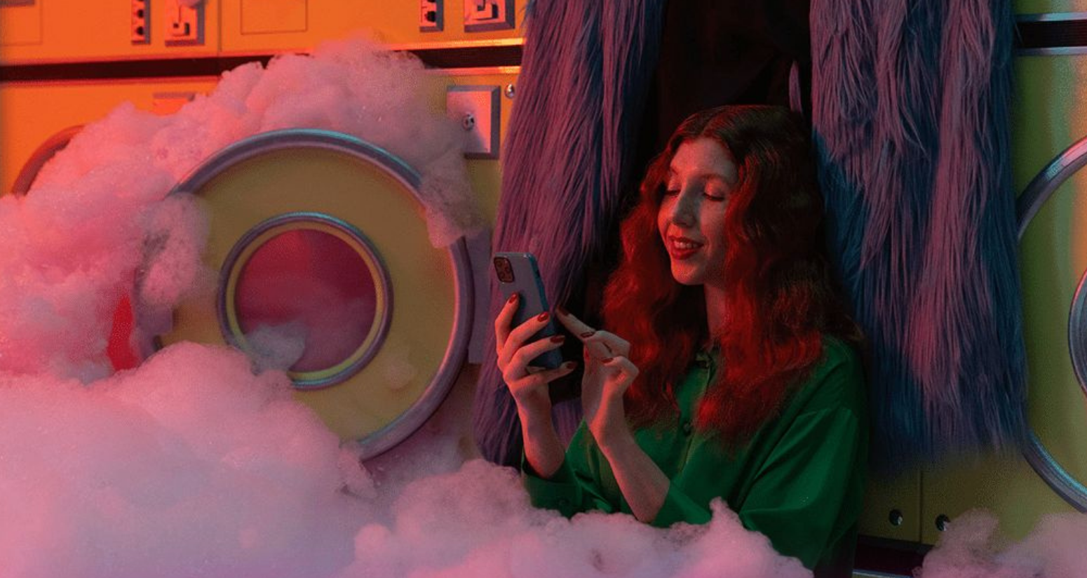 Image représentant une femme sur son téléphone au milieu de machines à laver et de mousse